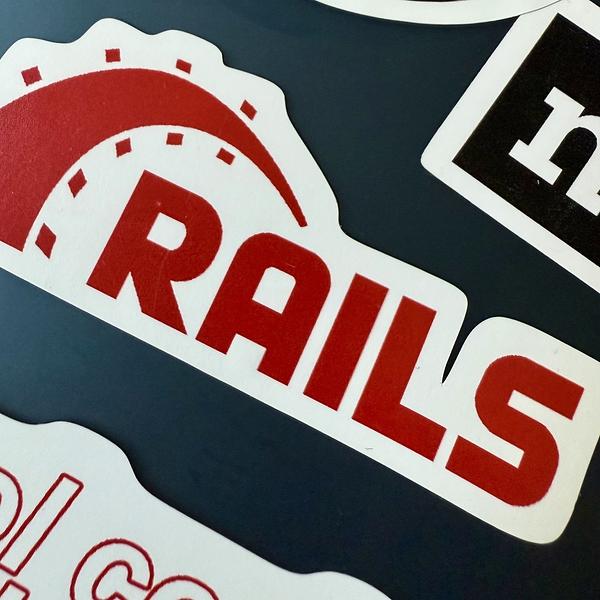 A sticker displays the logo and text RAILS, symbolizing the Ruby on Rails framework.
