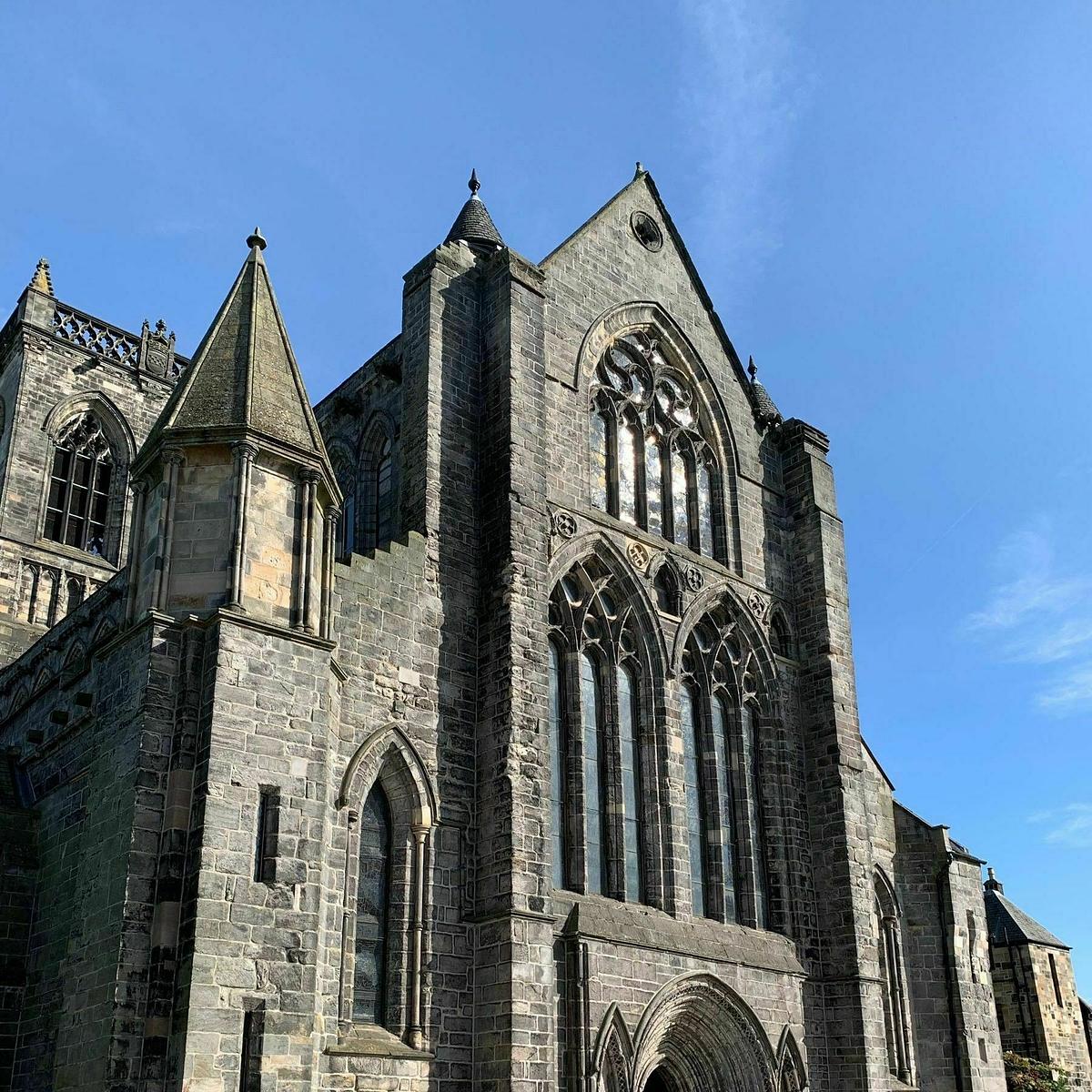 Auto-generated description: A large, historic stone cathedral stands against a clear blue sky, showcasing Gothic architectural details like pointed arches and tall stained glass windows.
