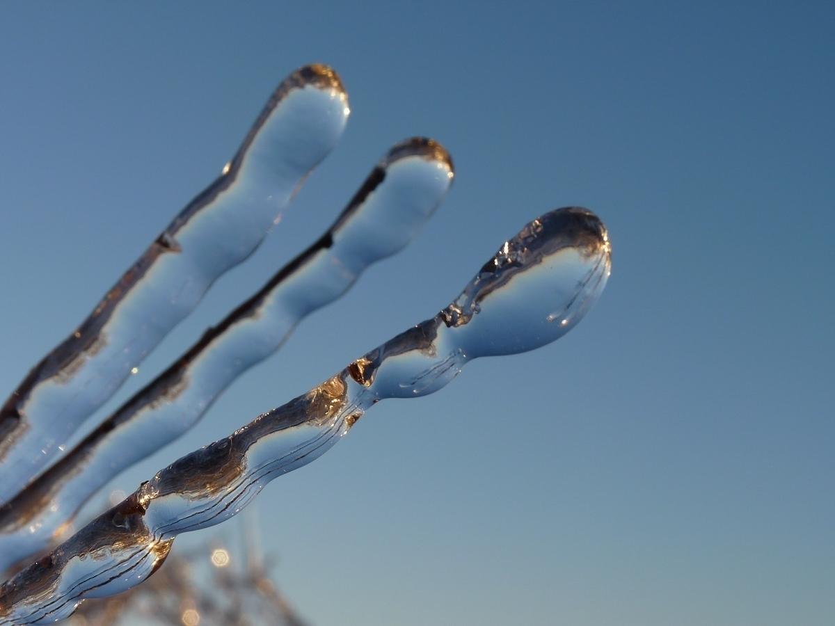 Clear icicles stretch against a blue sky.