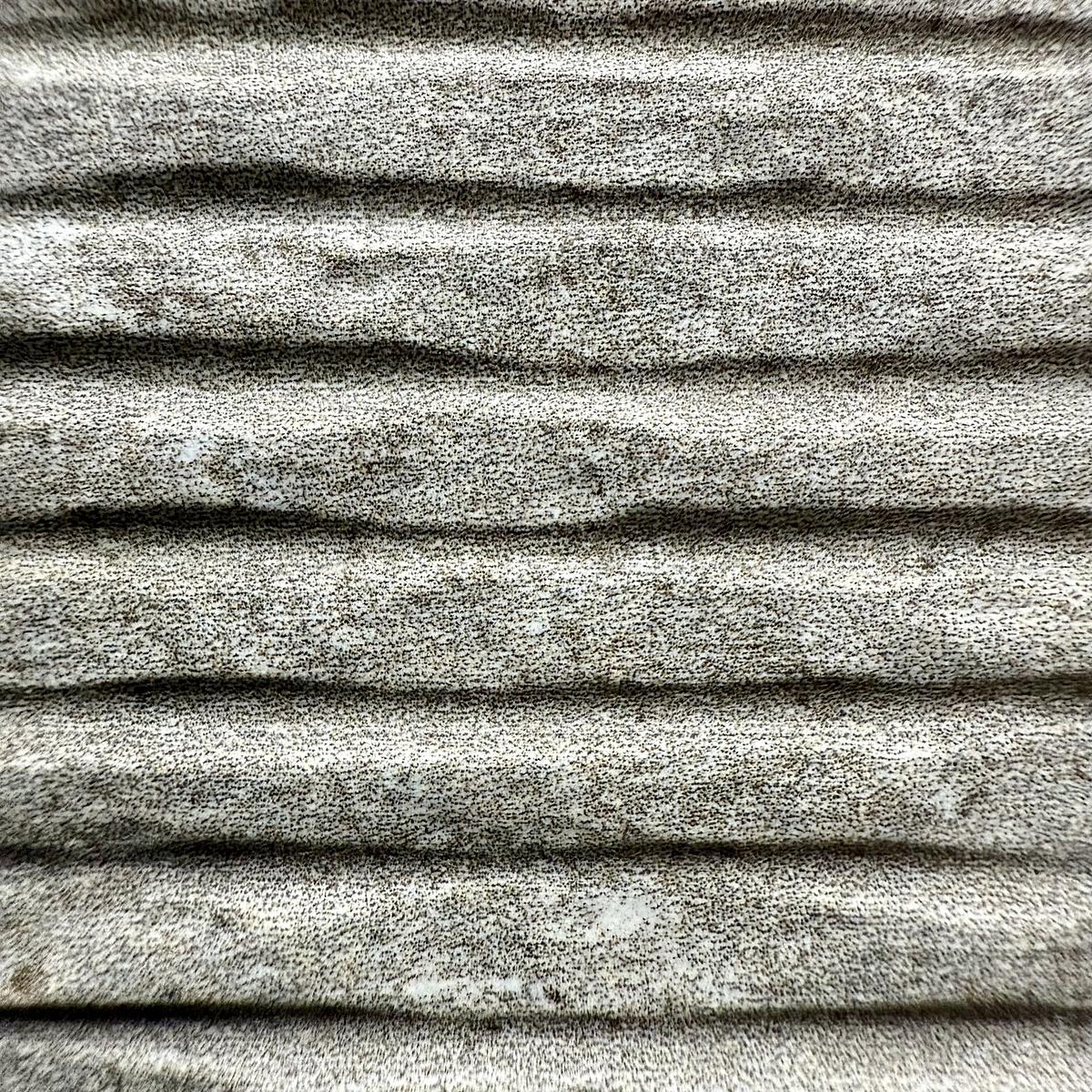 A close-up of a textured, ribbed tile with a speckled gray pattern.