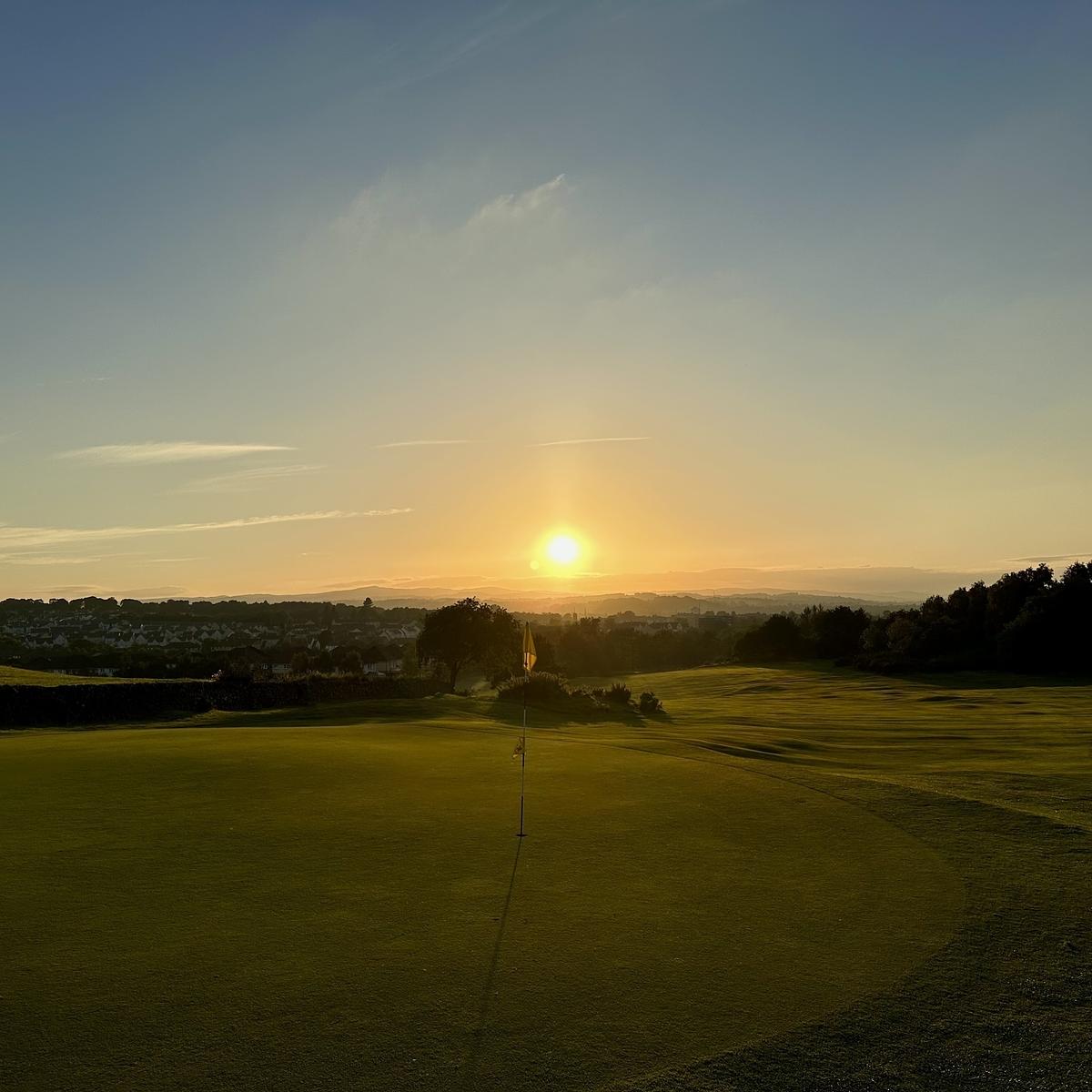 A scenic golf course is bathed in the warm glow of the sunset.
