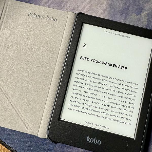 An open Kobo e-reader displays a page titled Feed Your Weaker Self beside its case.