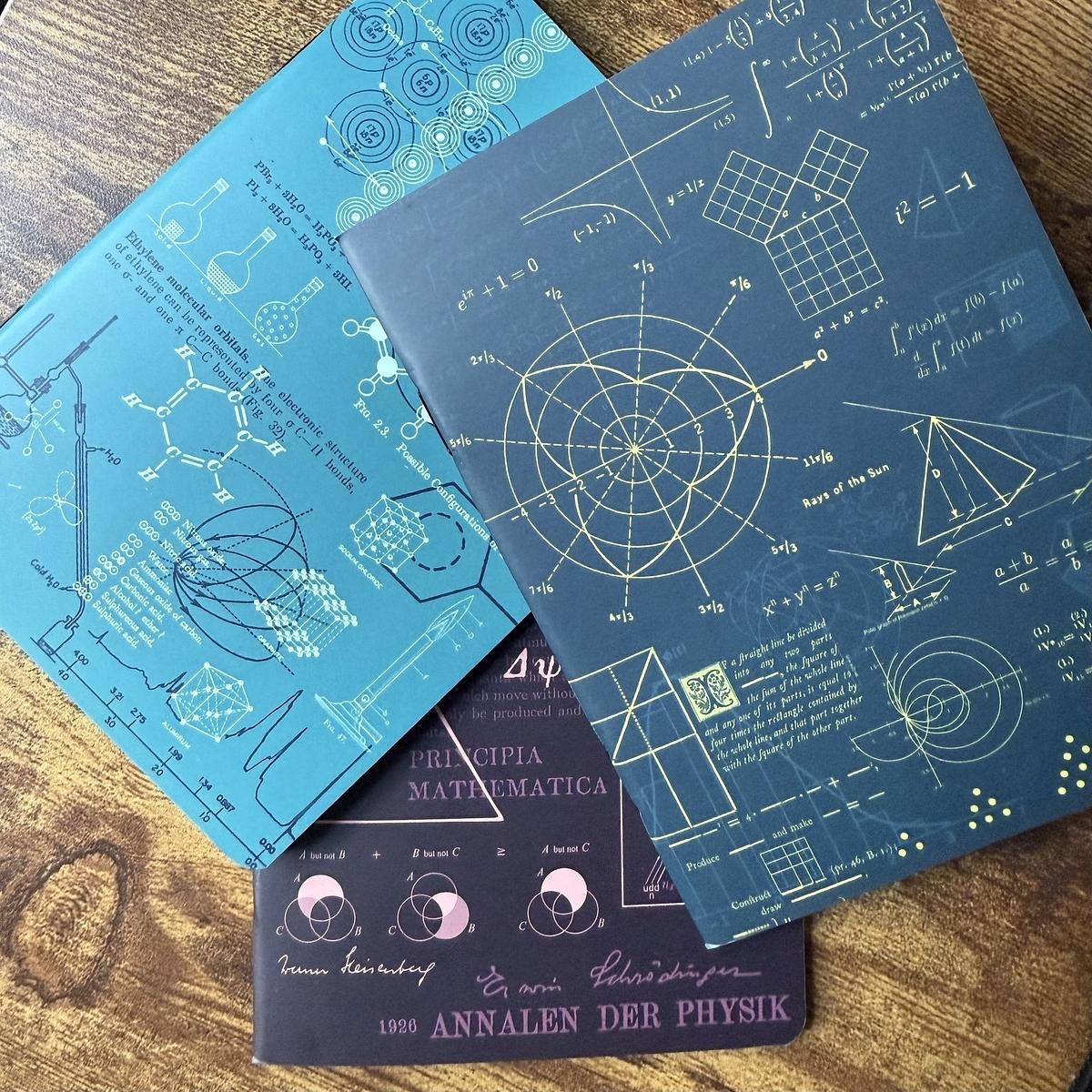 Three scientific-themed notebooks feature mathematical equations, geometry, and scientific diagrams on their covers.
