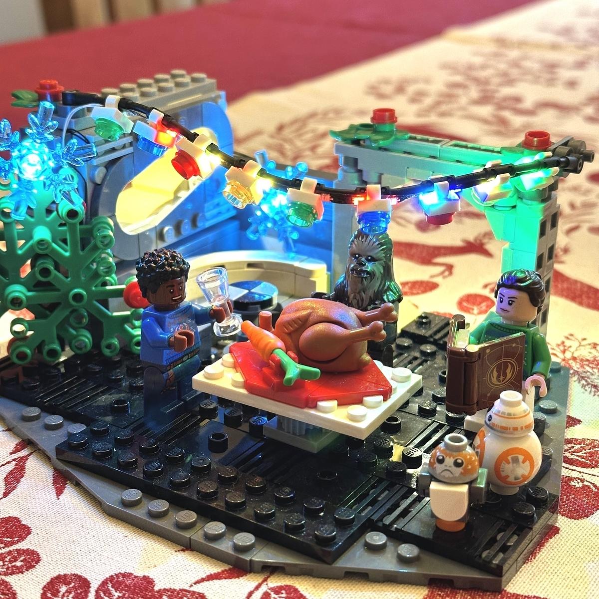 The Lego Christmas Millennium Falcon set with LED lights on a table.