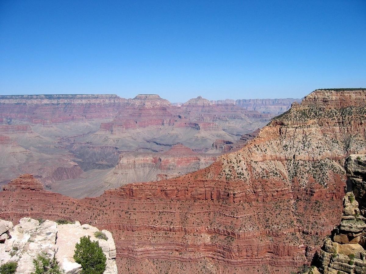 A breathtaking view of the Grand Canyon with layered red rock formations and a clear blue sky.