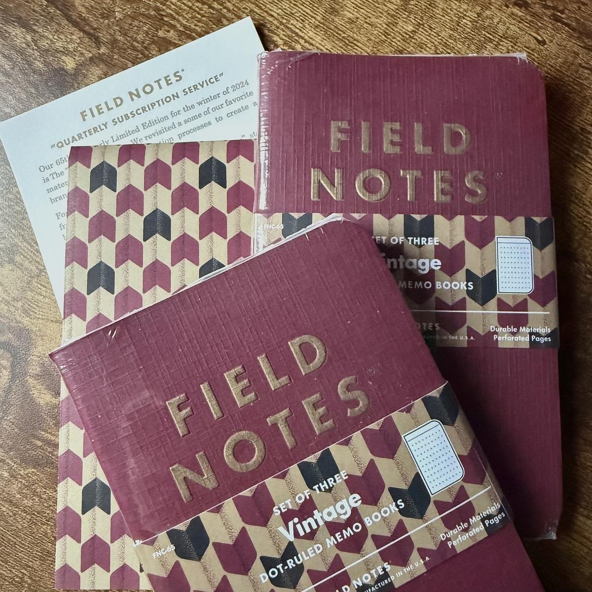 Several Field Notes memo books featuring vintage designs are placed on a wooden surface.
