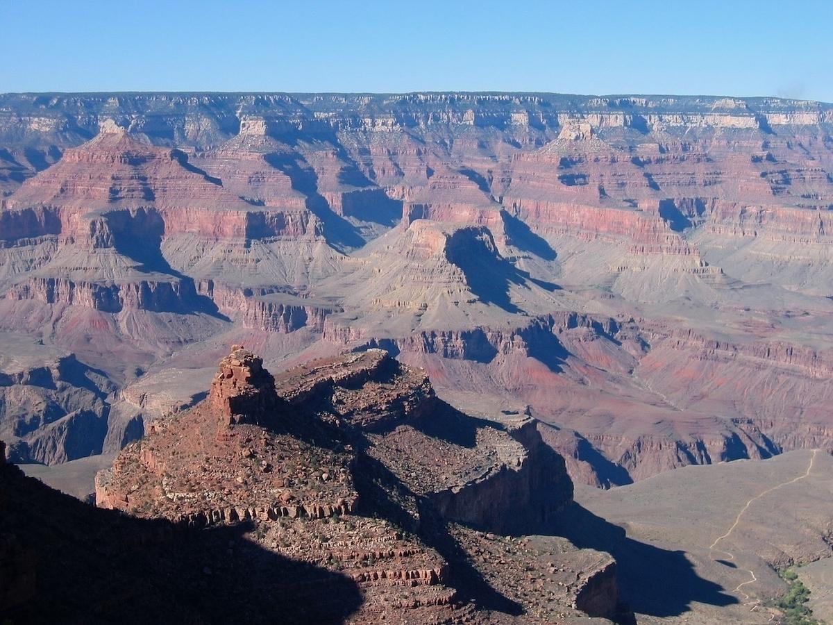A vast and colorful landscape of the Grand Canyon is depicted, showcasing its layered rock formations and deep valleys.